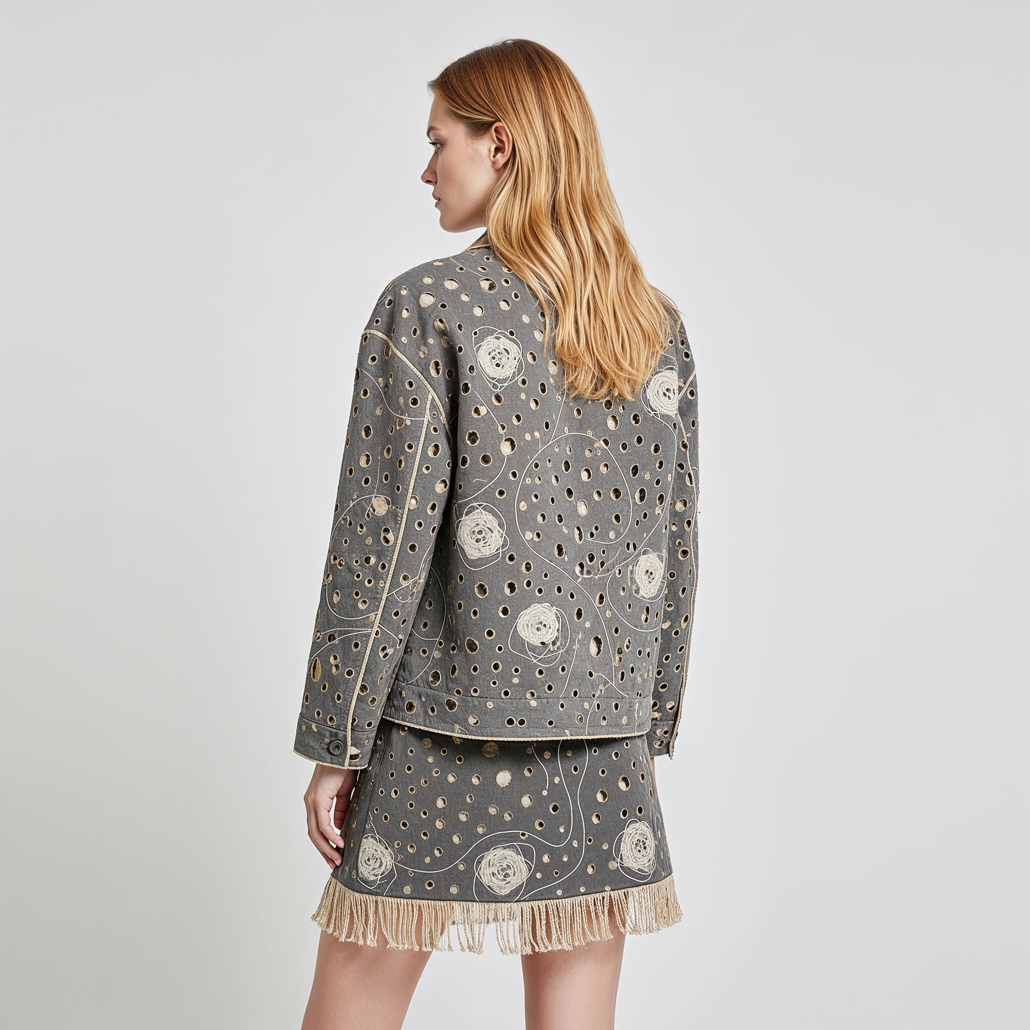 Woman wearing a gray embroidered jacket and skirt set on a plain background