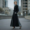 Woman in a long black skirt and top set standing on an urban street with buildings in the background